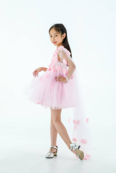 Portrait isolierte Studioaufnahme von kleinen asiatischen niedlichen Ballerina-Kind in rosa schönen Ballettkleid mit High Heels stehend lächelnd posiert Eleganz Geste vor weißem Hintergrund. - Foto, Bild