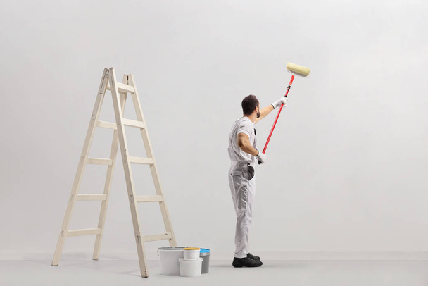 Ladder and buckets in a room and decorator painting a wall isolated on white background - Foto, Imagem