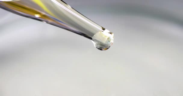 Átlátszó folyadék arany árnyalatú cseppek üveg pipetta lassított 4k film - Felvétel, videó