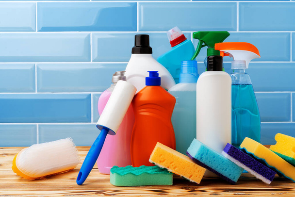 Household detergents and cleaning tools against blue tile background - Foto, imagen