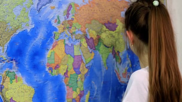 Ένα κορίτσι σχολικής ηλικίας μελετά την τοποθεσία των χωρών στον παγκόσμιο χάρτη - Πλάνα, βίντεο