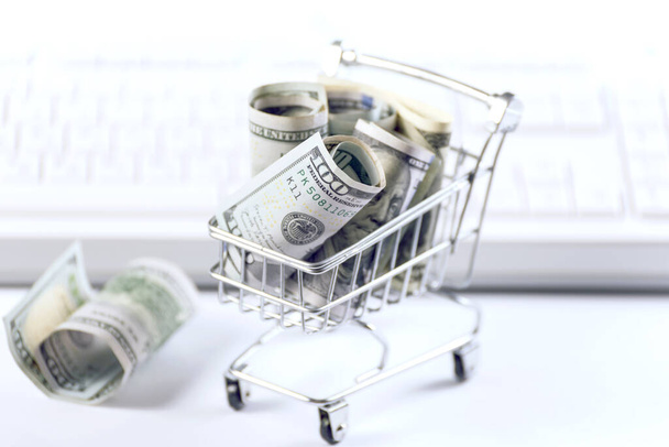 Dollar bill money in a shopping cart against blurred computer keyboard. Online business concept. - Fotoğraf, Görsel