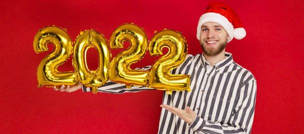 Człowiek w świątecznym kapeluszu trzyma numery 2022. Wkrótce nadejdzie Nowy Rok. - Zdjęcie, obraz