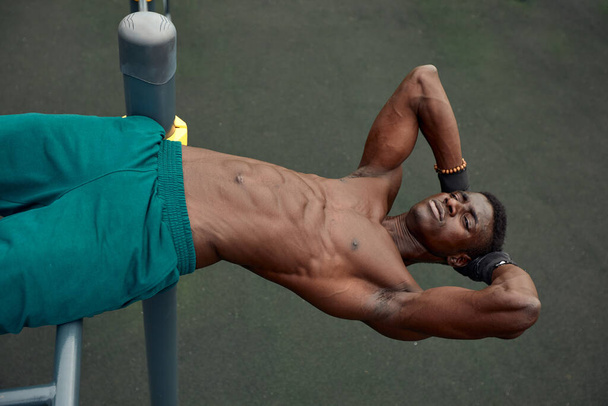 Young black man doing crunches outdoors. He is in a park. - Photo, Image