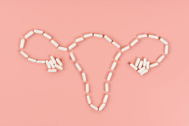 De baarmoeder is gelegd uit tabletten op een roze achtergrond. Ruimte voor tekst - Foto, afbeelding