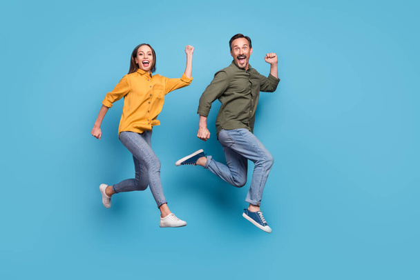 Full size profile photo of two delighted persons raise fists celebrate success triumph isolated on blue color background - Fotó, kép
