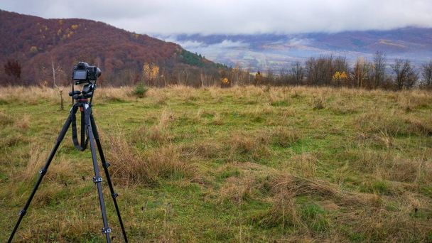 Fotograferen met een camera van een herfstlandschap met mist in een bergachtig gebied - Foto, afbeelding
