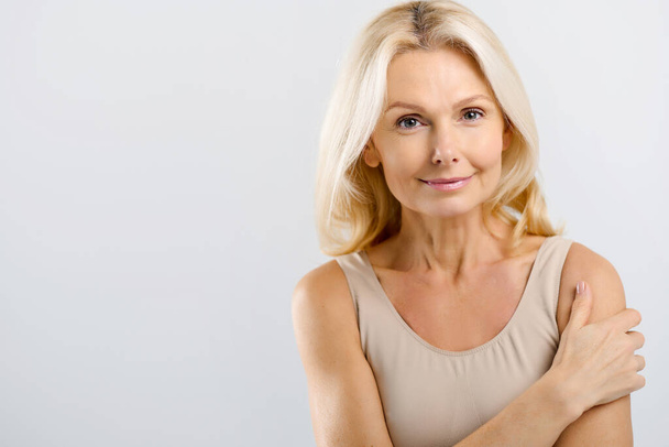 Good-looking beautiful middle-aged woman posing in studio over grey - Photo, Image