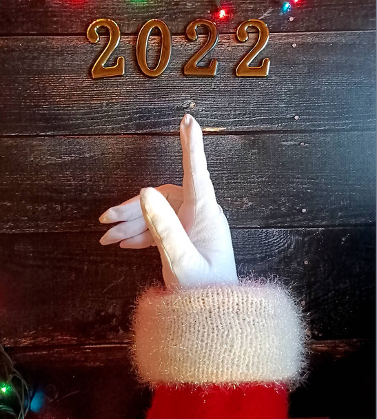Крупный план руки Санты в перчатках, жест, указывающий на цифры 2022 - Фото, изображение