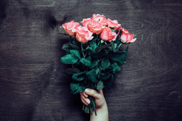 女性の手は木製の背景に柔らかいピンクのバラのロマンチックな花束を保持休日の花のカード誕生日、結婚式、ハッピーバレンタイン、母の日の創造的なコンセプトトップビューフラットレイ. - 写真・画像