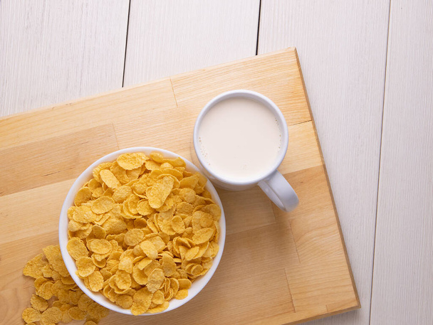 Cornflake-Müsli in einer Schüssel mit Milch auf hellem Hintergrund, schnelles Frühstück - Foto, Bild