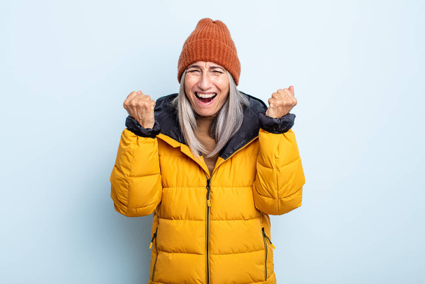 middle age gray hair woman shouting aggressively with an angry expression. cold weather concept - Photo, Image