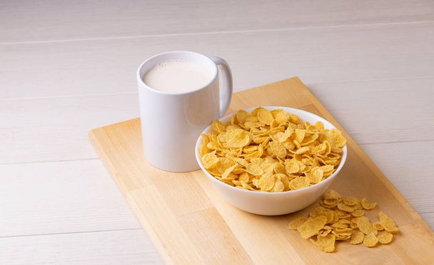 Cornflake granen in een kom met melk op lichte achtergrond, snel ontbijt - Foto, afbeelding