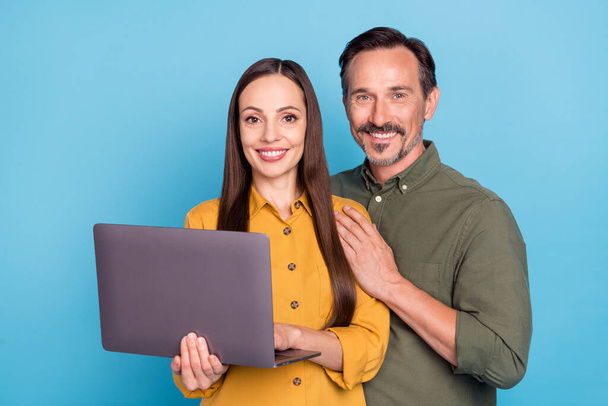 Photo of happy positive mature man and woman couple hold hands computer isolated on blue color background - Foto, Bild