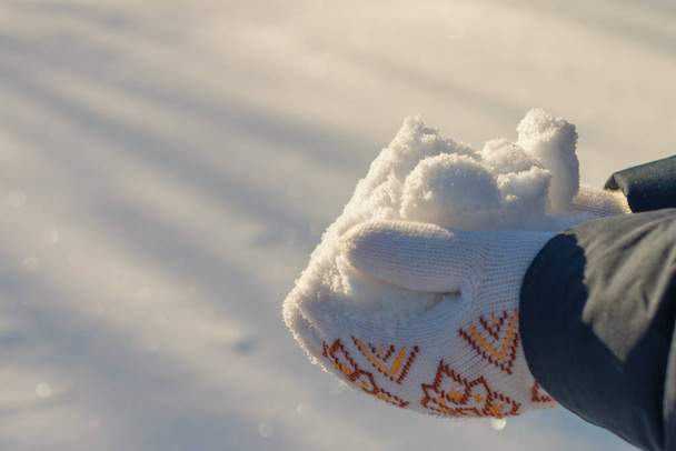 sonniger Tag, Hände halten einen Haufen sauberen glitzernden Schnees in Fäustlingen in den Händen - Foto, Bild