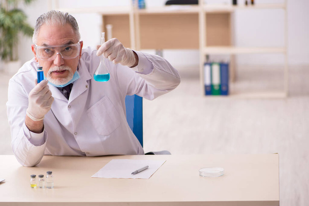 Παλιός άντρας χημικός που εργάζεται στο εργαστήριο κατά τη διάρκεια πανδημίας - Φωτογραφία, εικόνα