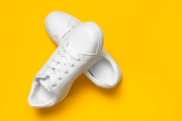 White women's leather sneakers on yellow background top view flat lay. Stylish youth sneakers, sports shoes, genuine leather footwear. Minimalistic shoe store advertising fashion style Shoe background. - Fotoğraf, Görsel