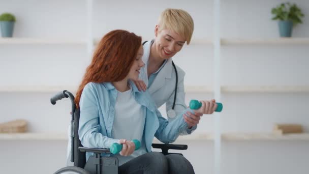 Reabilitação após acidente. Média idade médico mostrando exercício com halteres para menina com deficiência - Filmagem, Vídeo