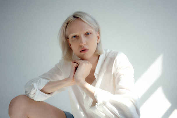 An attractive Russian blonde female wearing a white shirt posing in a studio - Foto, Bild