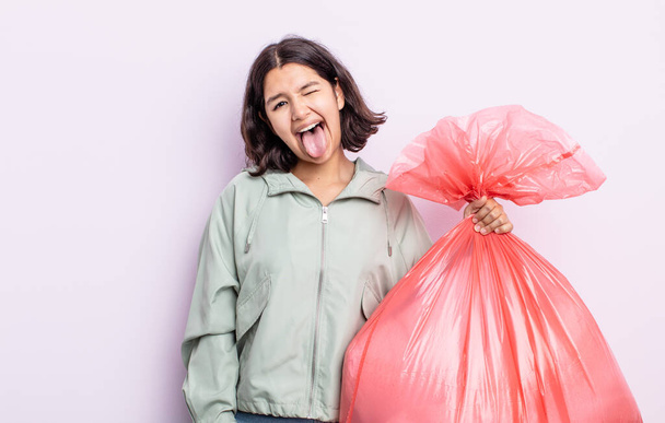 pretty young woman with cheerful and rebellious attitude, joking and sticking tongue out. trash bag concept - Фото, зображення