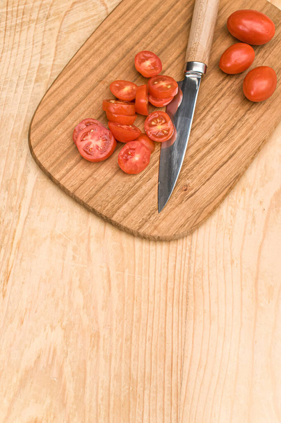 tomates datterini con tabla de cortar y cuchillo en una superficie de madera con espacio de texto - Foto, imagen