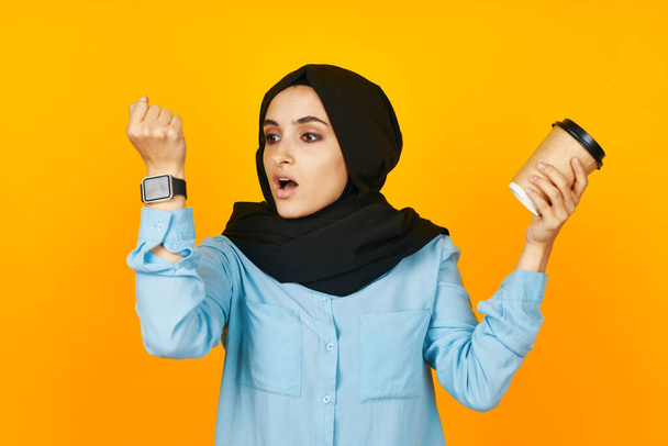 arab woman with clock in hands technology emotions yellow background - Foto, afbeelding