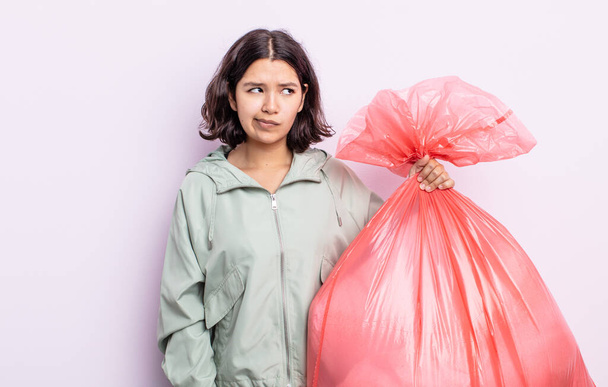 pretty young woman feeling sad, upset or angry and looking to the side. trash bag concept - Fotografie, Obrázek