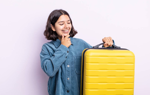 pretty young woman smiling with a happy, confident expression with hand on chin. travel case concept - Φωτογραφία, εικόνα