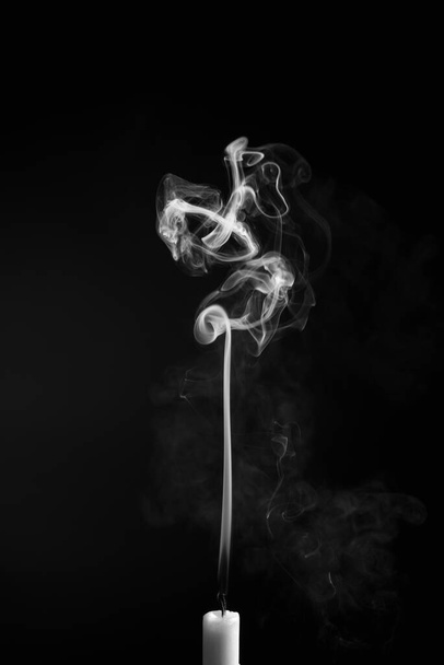 A vertical shot of the smoke of an extinguished candle isolated on a black background - Фото, зображення