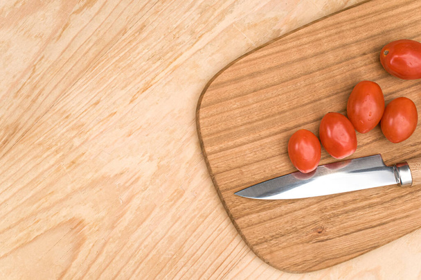 datterini tomatoes with chopping board and knife on a wooden surface with text space - Foto, imagen