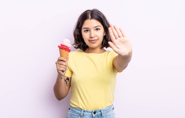 pretty young woman looking serious showing open palm making stop gesture. ice cream concept - Photo, image