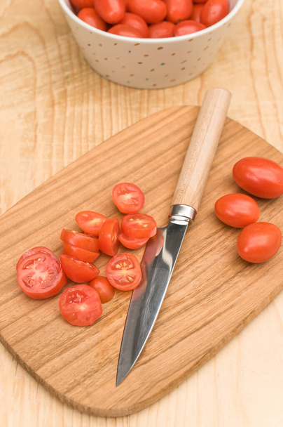 bol blanc aux tomates datterini avec planche à découper et couteau sur une surface en bois avec espace texte - Photo, image