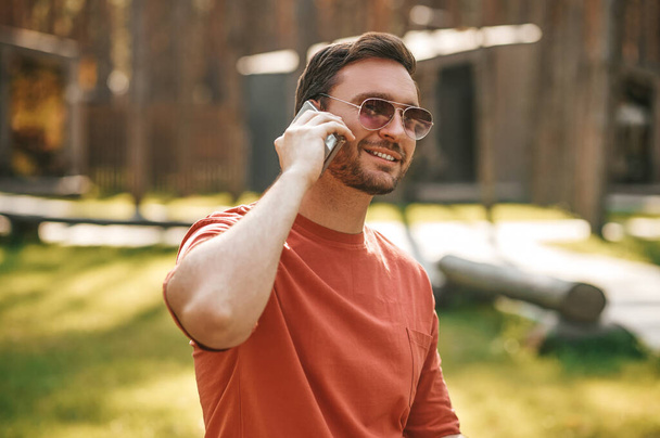 Atractivo hombre joven adulto comunicándose por teléfono inteligente - Foto, Imagen