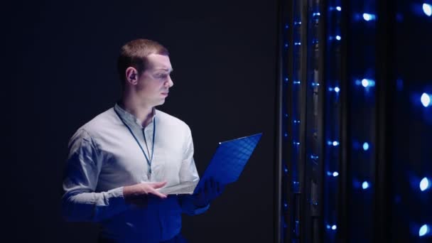 Un técnico con un portátil en la sala de servidores - Metraje, vídeo
