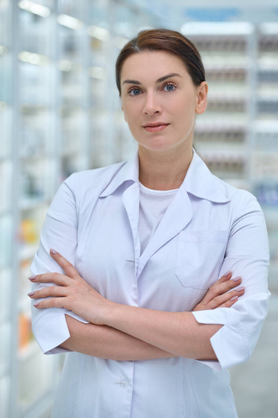 Confident woman in lab coat in pharmacy hall - 写真・画像
