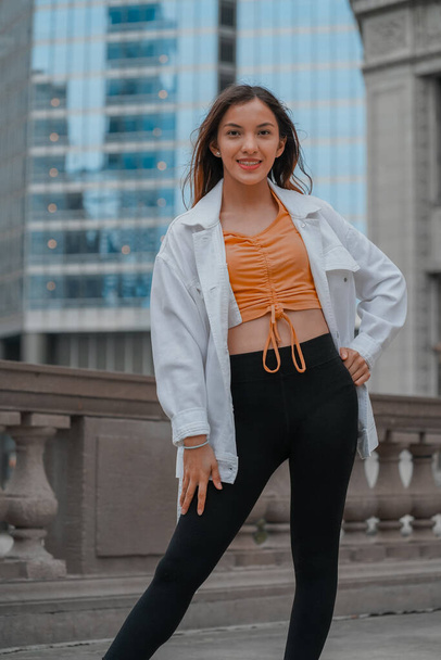 A vertical of a cheerful stylish young beautiful Hispanic female posing on the street - Photo, image
