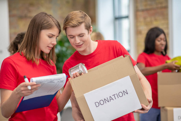 Volunteers in red thsirts taking part if donations distribution - Φωτογραφία, εικόνα