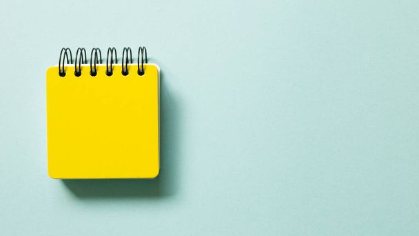 Yellow note pad isolated on blue background. top view, copy space - Photo, image