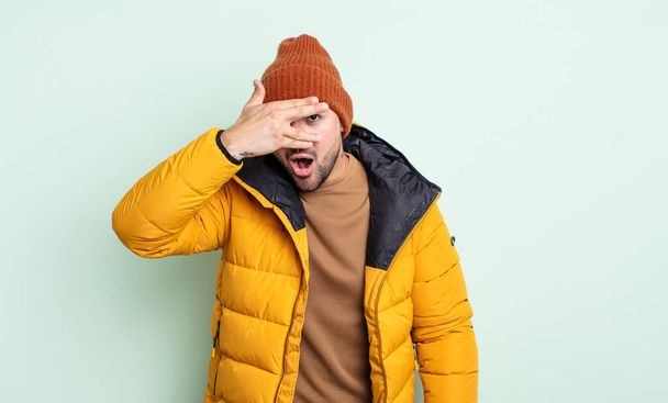 young handsome man looking shocked, scared or terrified, covering face with hand. cold weather concept - Foto, Bild