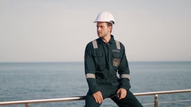 Fiatal jóképű férfi kikötői ügynök walkie-talkie rádióval a kezében, tengeri kikötőben dolgozik. - Felvétel, videó
