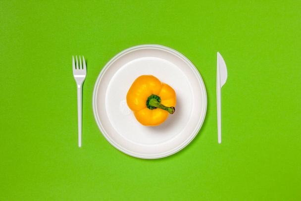 Yellow bell pepper on a white plate, fork and knife, dieting, healthy food concept. Food creative concept. Top view Pink Background Flat Lay with copy space. - Zdjęcie, obraz
