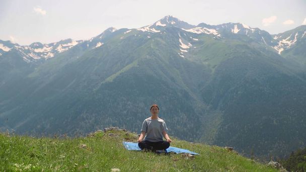 Een jonge vrouw doet yoga op de toppen van de bergen. Sporttoerisme - Foto, afbeelding