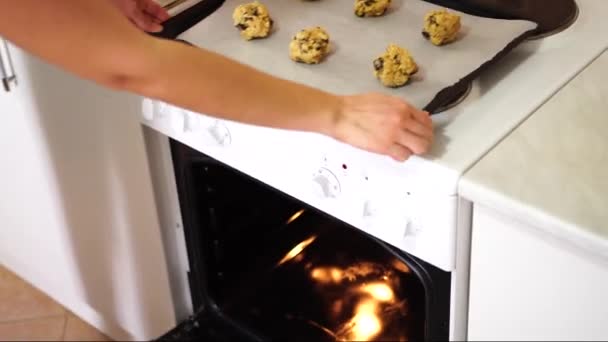 Mädchen legt ein Backblech mit amerikanischen Plätzchen mit Schokoladenchips in den Ofen - Filmmaterial, Video