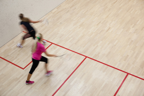 Two female squash players in fast action on a squash court (moti - Фото, изображение
