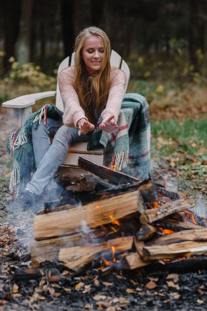 νεαρή γυναίκα κάθεται δίπλα στη φωτιά σε χρωματιστό ζεστό πάγο ζέσταμα φωτιά θερμότητα μακριά μαλλιά - Φωτογραφία, εικόνα