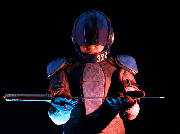 Cyberpunk future concept. Bionic cyborg police officer with short samurai sword stands in dark. Halfman robot looks at camera. Futuristic science fiction scene. - Фото, зображення