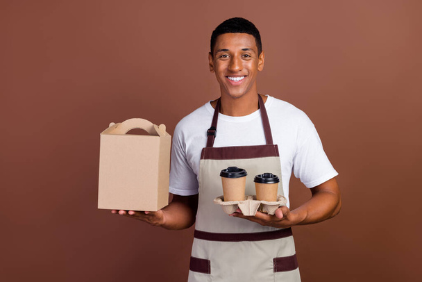 Photo of young cheerful afro man hold espresso cappuccino to-go delivery isolated over brown color background - Фото, изображение