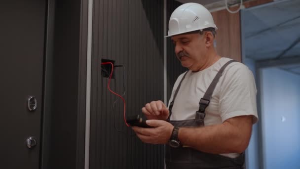 Portret Elektricien controleert de werking van de muur besturingseenheid van lampen met het systeem van modern huis na installatie en reparatie - Video