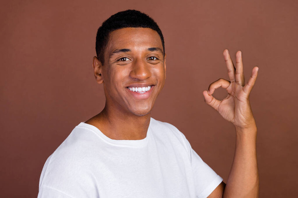 Profile side photo of young african man show finger okey symbol approve perfect isolated over brown color background - 写真・画像