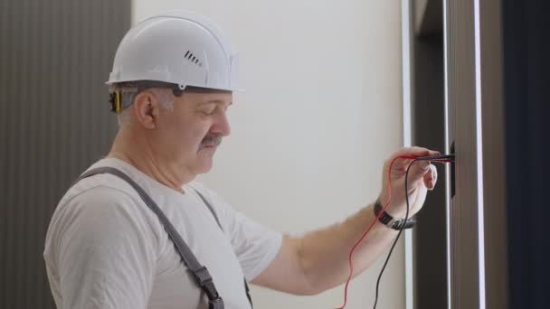 Eletricista verifica o funcionamento da unidade de controle de parede para lâmpadas e iluminação de paredes e teto com um sistema de casa moderna após a instalação e reparação - Filmagem, Vídeo